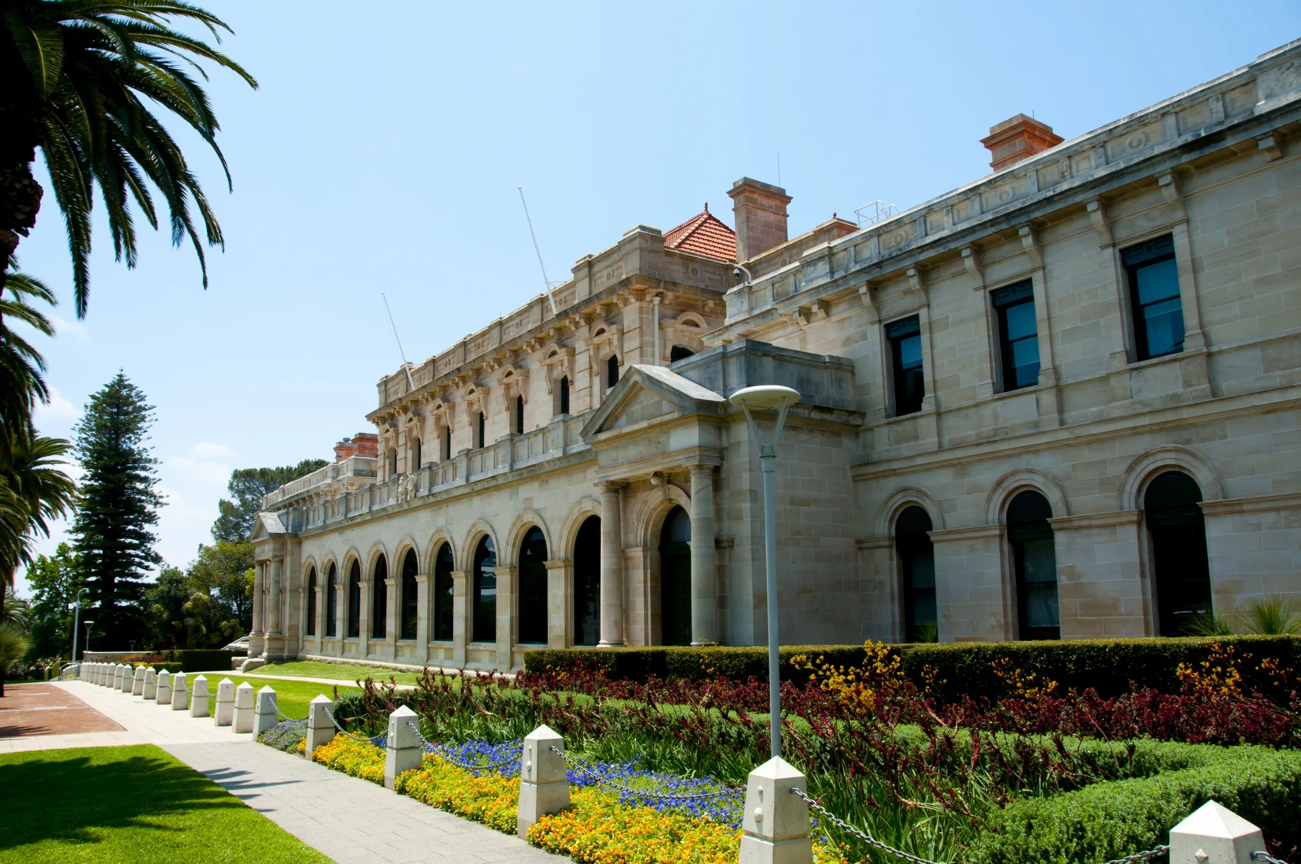 A grand stone building with arched windows and a manicured garden.