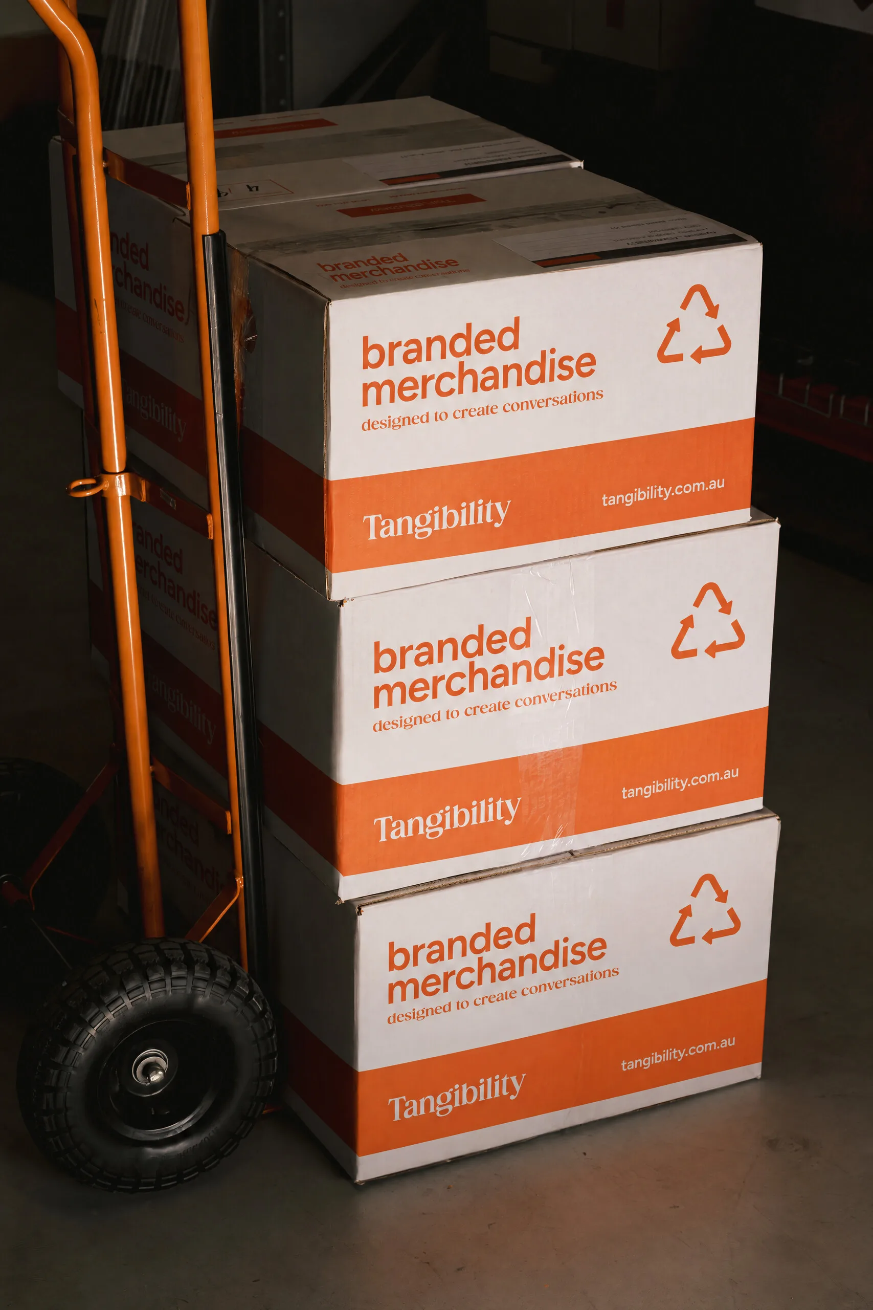 Stack of Tangibility branded merchandise boxes on a trolley.